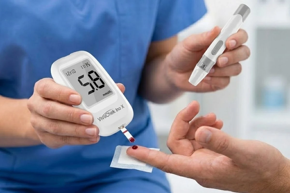 Primer plano de un enfermero con uniforme azul realizando una prueba de glucosa en sangre a un paciente utilizando un glucómetro VivaChek Ino X como dispositivo Point of Care (POCT).