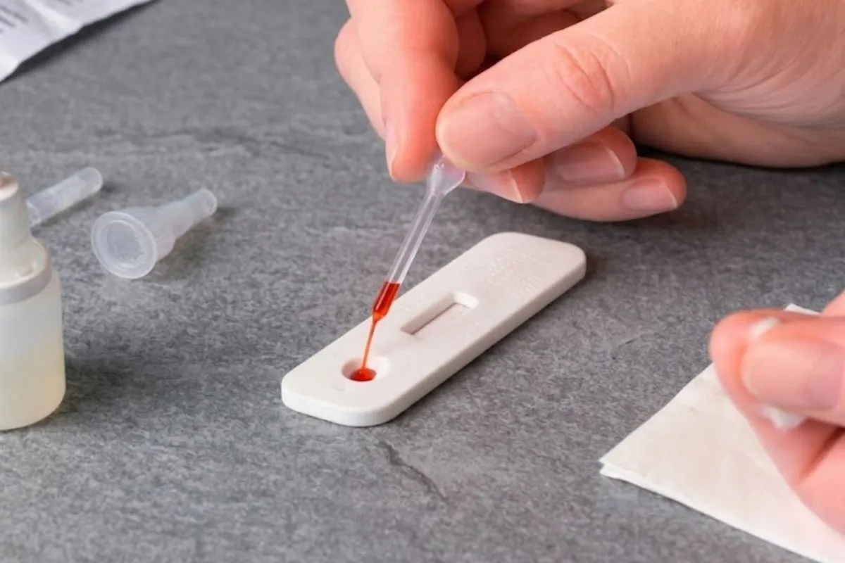 Profesional aplicando muestra en cassette de pruebas rápidas con pipeta